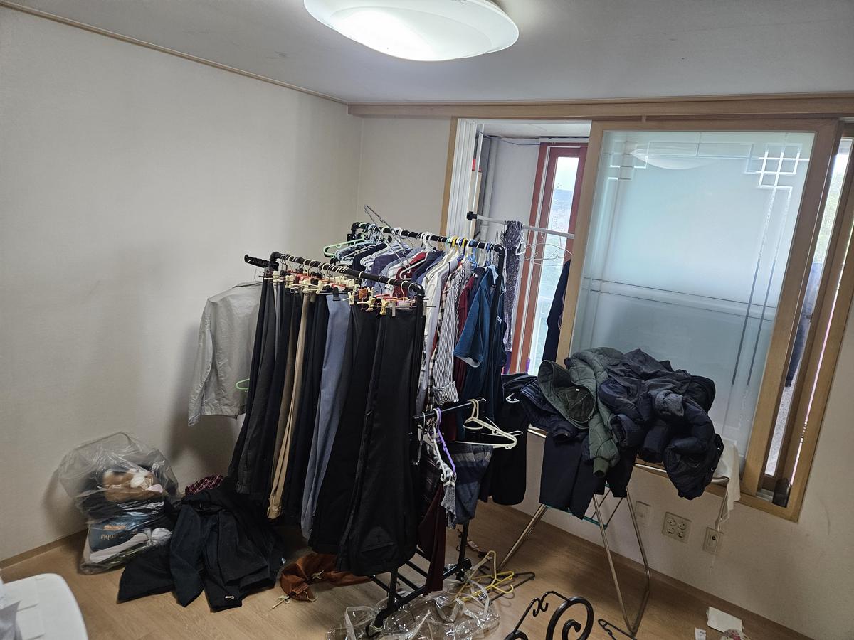 정리 전 옷걸이에 걸린 의류가 가득한 방